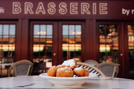 Beignets sit on a table on the patio at Brasserie by Niche.