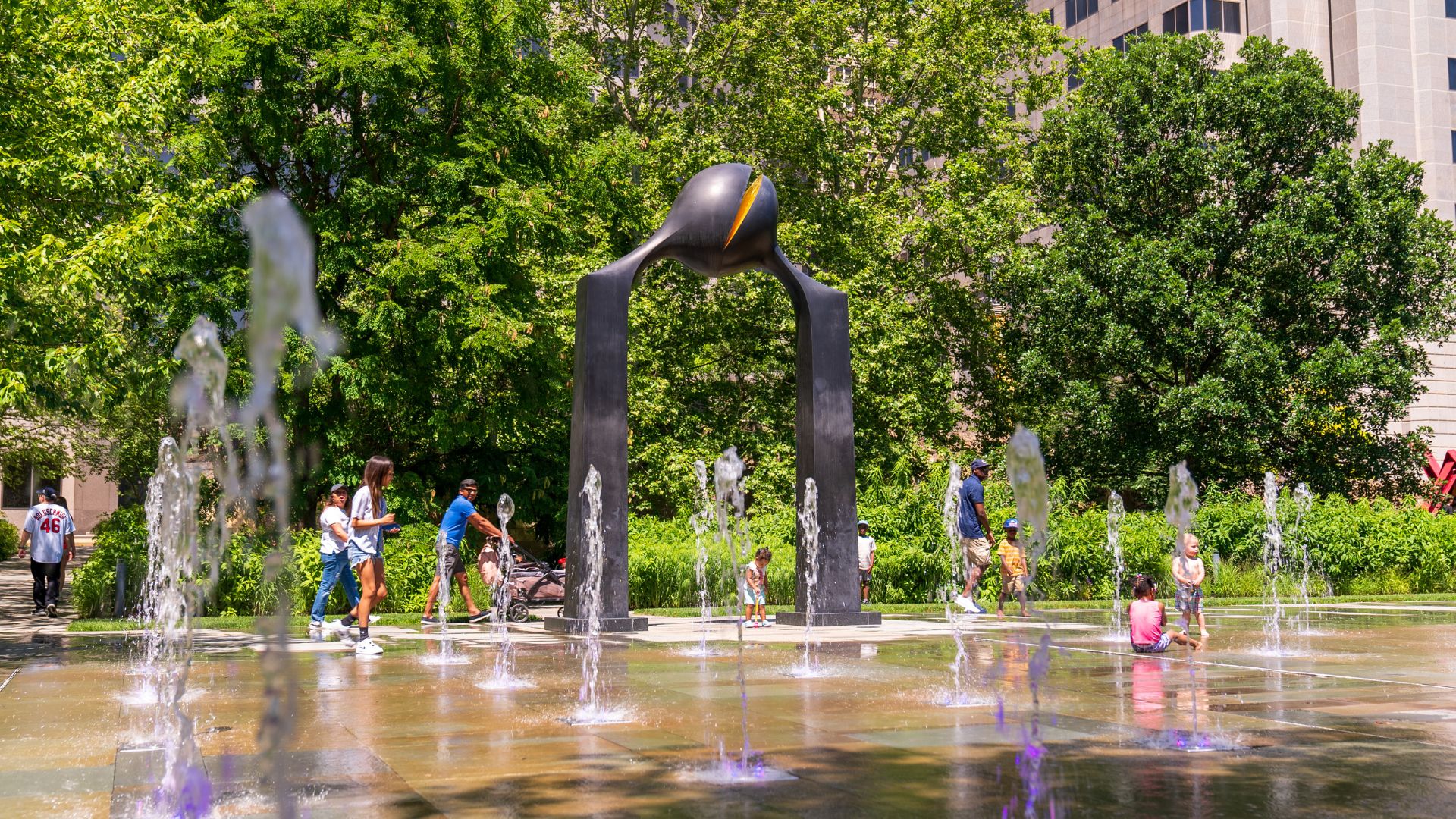 A family plays in the dancing fountains at Citygarden.