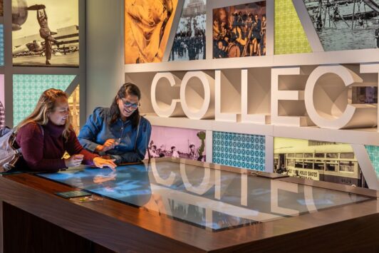 Two women use an interact display at the new permanent exhibition at the Missouri History Museum.