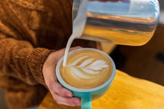 A barista pours a latte at Maypop Coffee and Garden Shop.