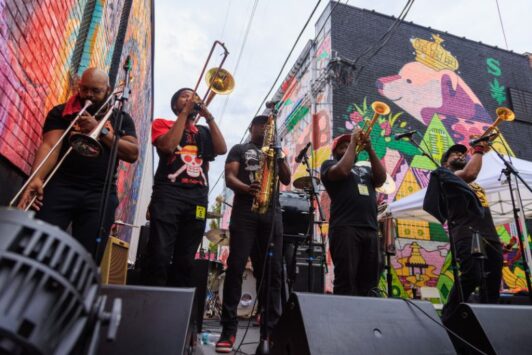 A brass band plays among the murals of Grand Center during Music at the Intersection.