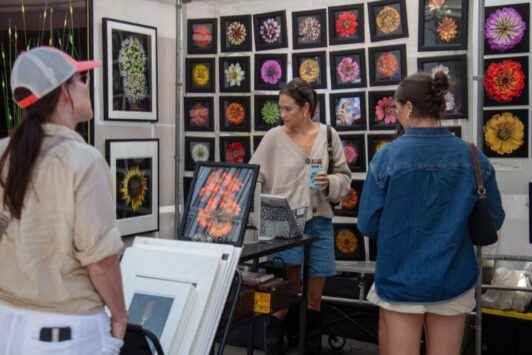 Women peruse gorgeous floral photography at the Saint Louis Art Fair in Clayton.