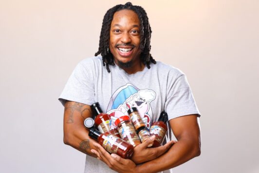 Keyon Watkins, owner of Sauce So Good, holds an armful of products available at Soulard Farmers Market.